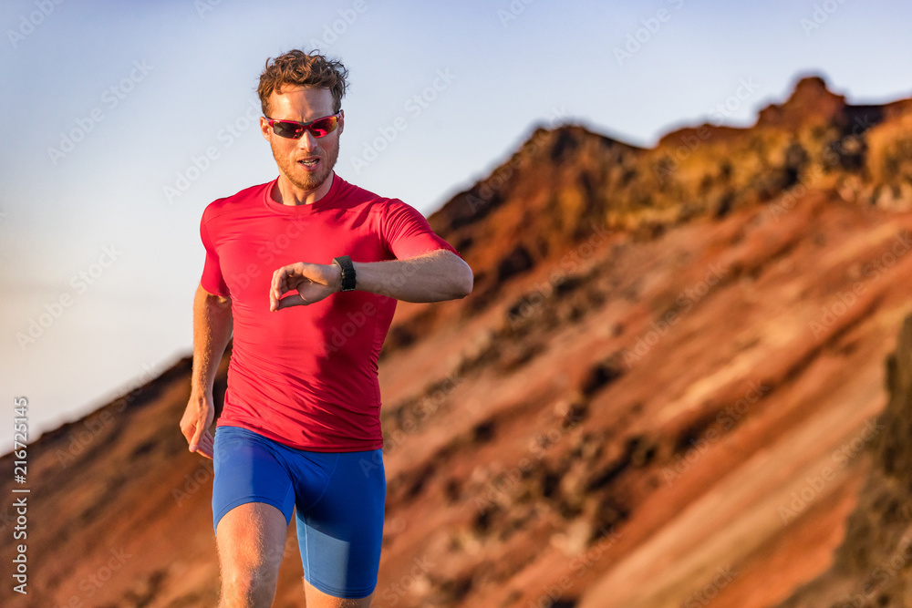 Athlete runner checking cardio on sports smartwatch jogging on outdoor run track. Running man wearing sunglasses and tech wearable device looking at watch during training Stock Photo | Adobe Stock