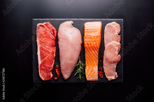 Group of animal proteins, chicken, meat, fish and pork on a black background photo