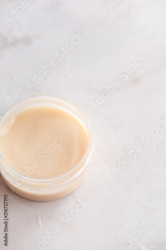 Spa cosmetics  open jar with skin care product on white marble background from above. Beauty blogging concept. Copyspace