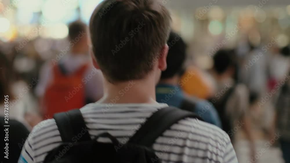 Following Shot of the Traveling Man with a Backpack Walking Through the Crowd of People in the Big City. Young Tourist Travilng or Boy Going to School.