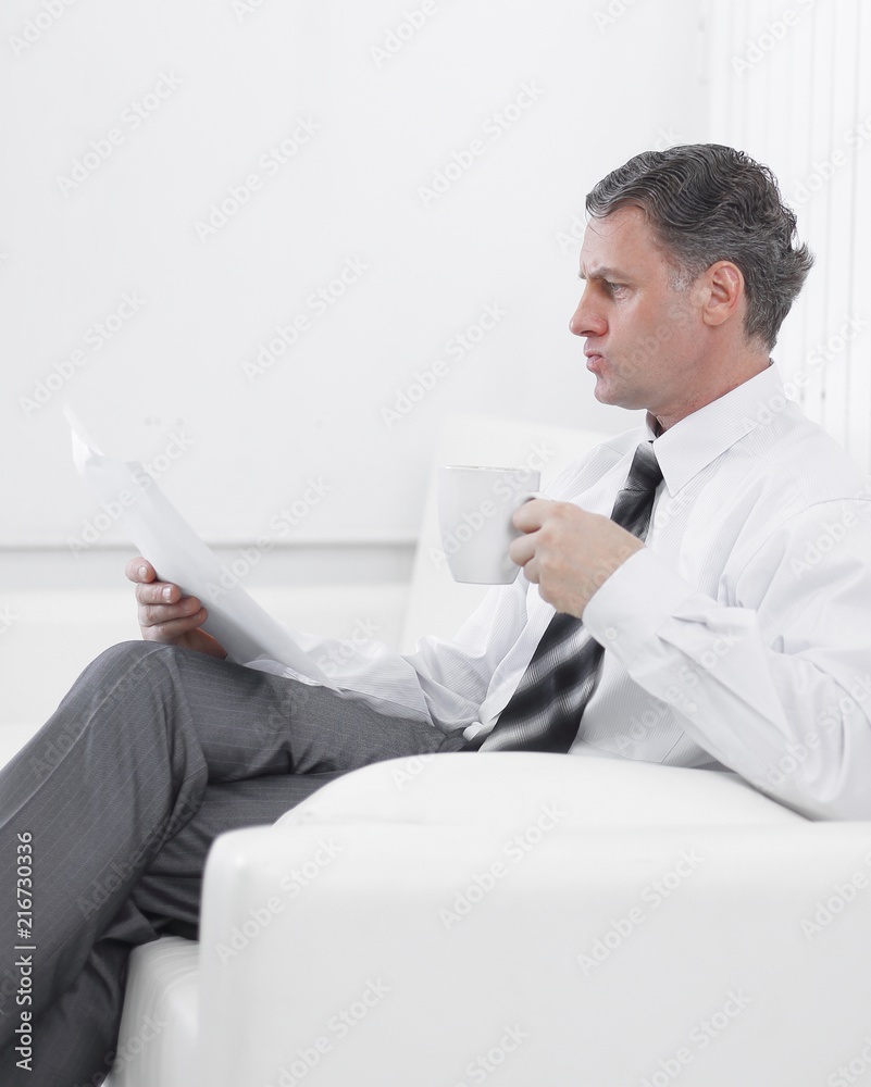 businessman reading a document while sitting in a chair in the hotel room. businessman reading a document while sitting in a chair in the hotel room.