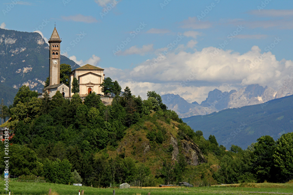 la chiesa parrocchiale di Castello emerge su un colle in Val di Fiemme (Trentino); sullo sfondo, le Pale di San Martino