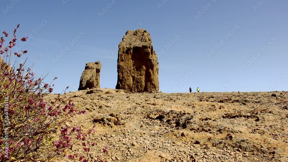 Two explorers going to Roque Nublo monolith in Gran Canaria island, Spain. Young men hiking on rocky arid biosphere reserve. Adventure, tourism attraction, nature connection concepts Two explorers going to Roque Nublo monolith in Gran Canaria island, Spain. Young men hiking on rocky arid biosphere reserve. Adventure, tourism attraction, nature connection concepts