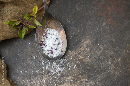 Purple Basil Herb Salt in Tarnished Spoon on Black Background with Fresh Sprig of Basil