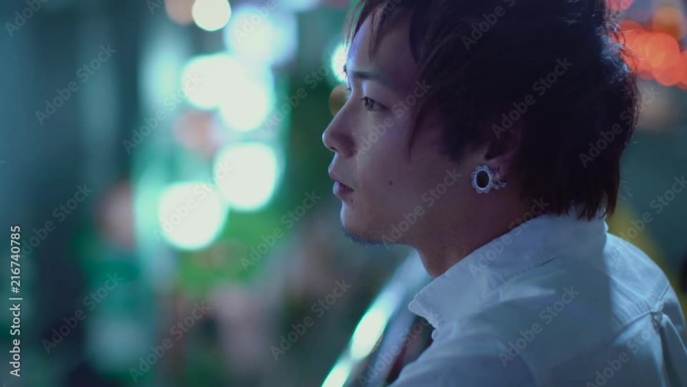 Portrait of the Handsome Japanese Alternative Man with Piercing. In the Background Big City Advertising Billboards Lights Glow in the Night. Portrait of the Handsome Japanese Alternative Man with Piercing. In the Background Big City Advertising Billboards Lights Glow in the Night.