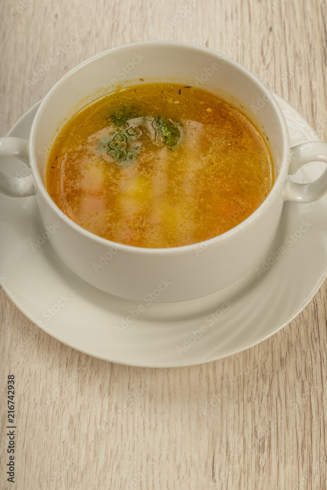 Plate with soup in a white plate on a wooden background. Plate with soup in a white plate on a wooden background.