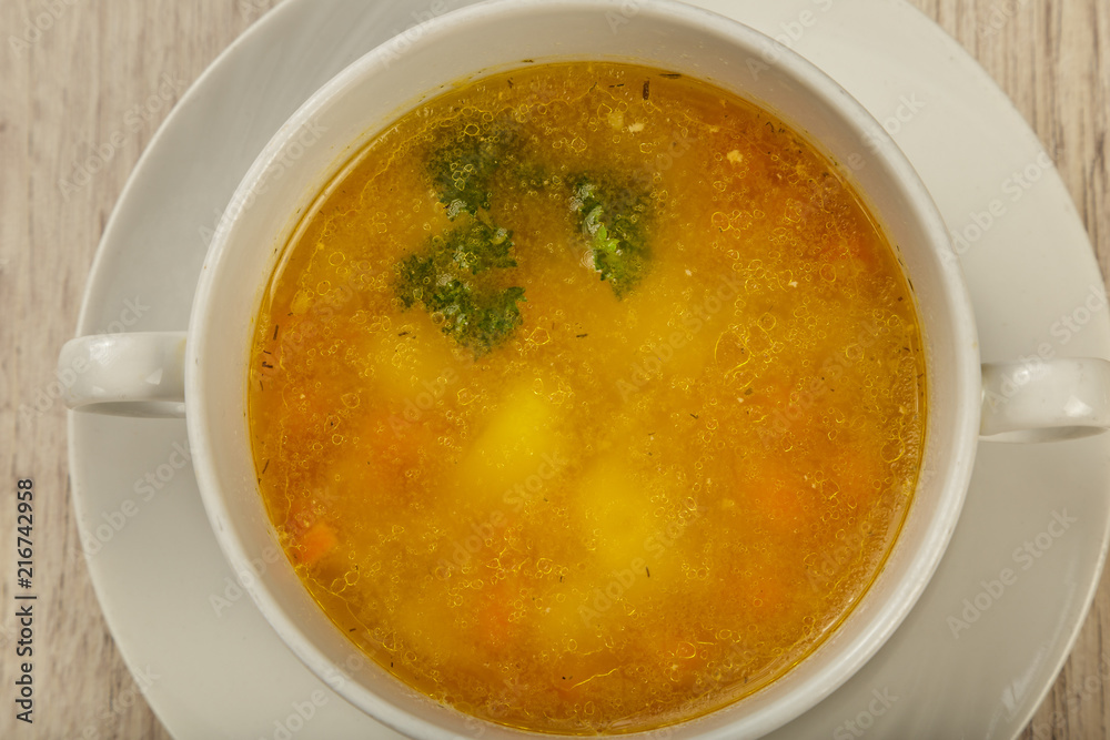 Plate with soup in a white plate on a wooden background.