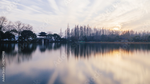 Sunset over West Lake in Hangzhou, China with Reflections of Trees and Pavilions