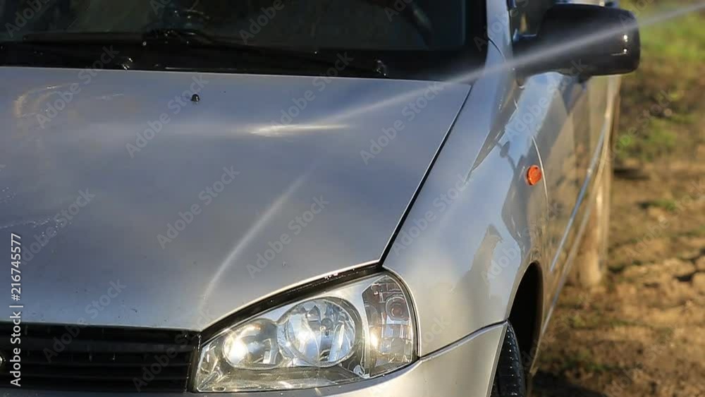 Young attractive man perfusing with water his silver car Young attractive man perfusing with water his silver car