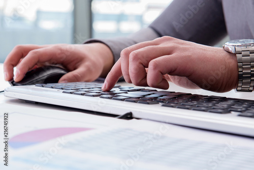 Finance professional working on keyboard with reports