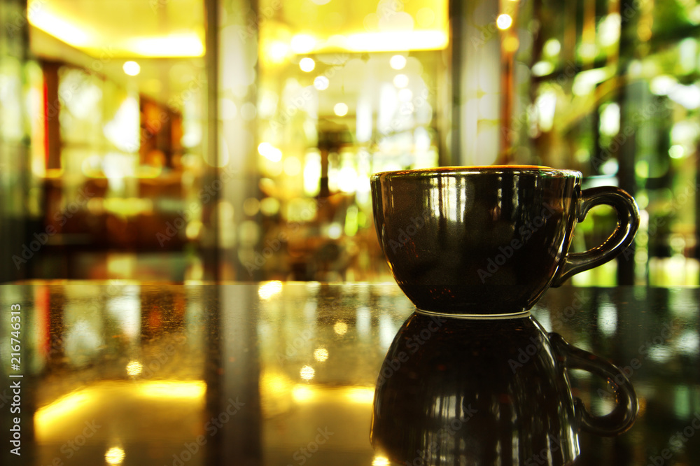 black cup of hot coffee on light reflect table in pub bar cafe background
