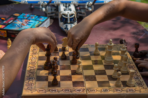 kids playing chess in garden with blurred toys on background 