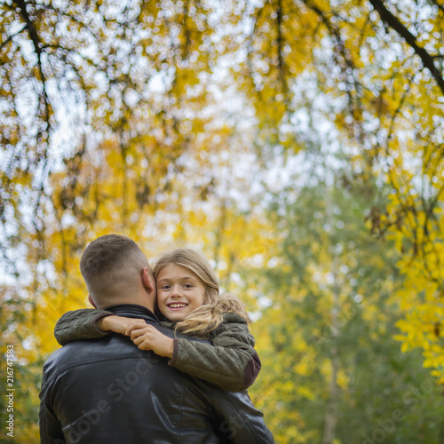portrait of pretty little girl and young father walking in beautiful autumn park