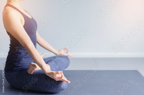 Young woman practice yoga in background.Young people do yoga indoor.Close up hands in meditating gesture. Copy space.