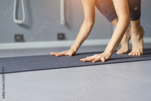 Young woman practicing yoga in gray background.Young people do yoga indoor.Close up hands in meditating gesture. Copy space.