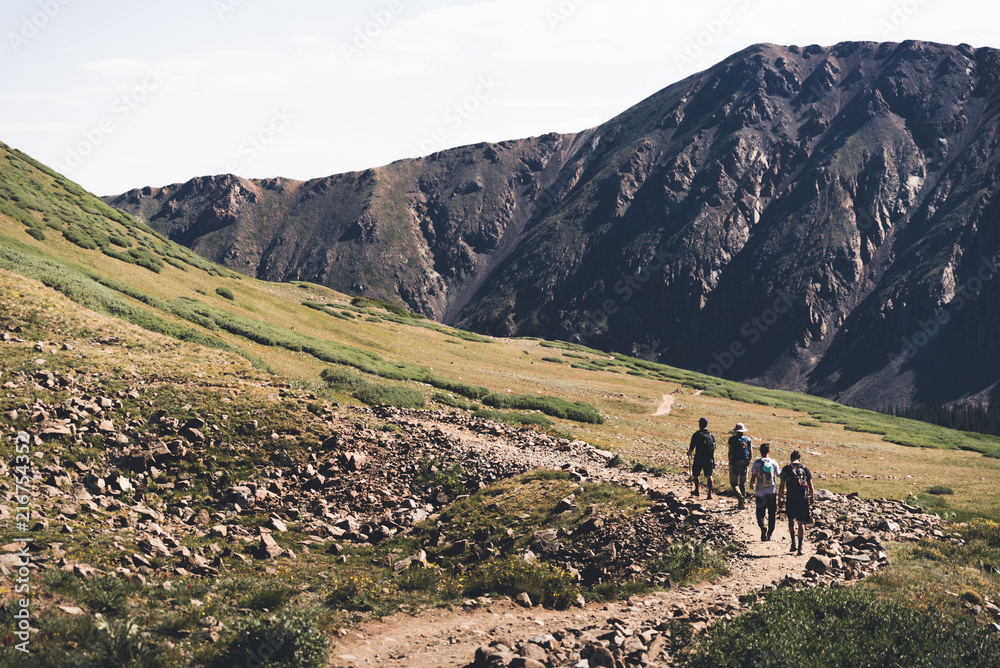 Four people walking on a trail in the mountains of Colorado. 