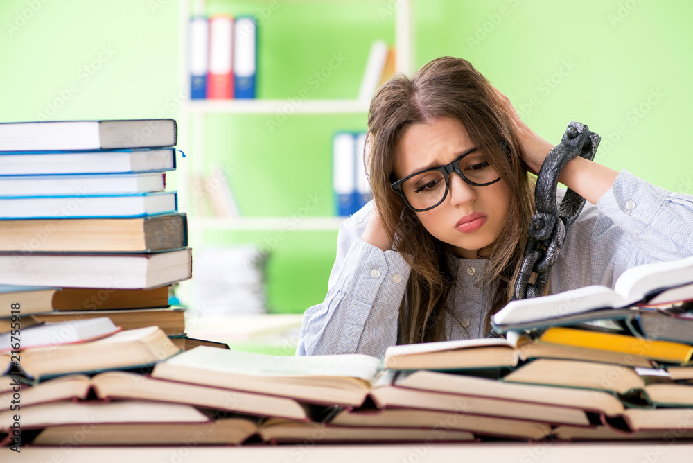 Young female student chained to the desk and preparing for exams Young female student chained to the desk and preparing for exams