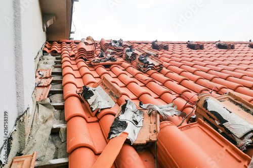 фотографія Old moldy roof tile being replaced with new tiles