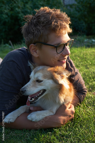 Smiling teenager boy embraces his dog with a face full of joy and excitement
