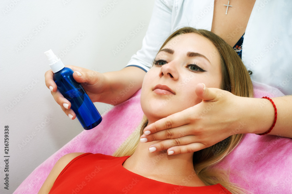 Naklejka premium The girl doing the facial massage . Young beautiful woman on cosmetic procedures .