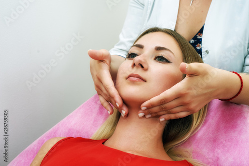 The girl doing the facial massage . Young beautiful woman on cosmetic procedures .