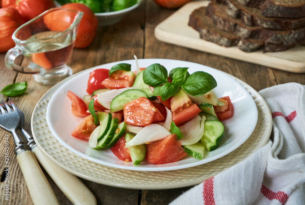 Fresh vegetable salad with ripe tomatoes and cucumbers on a plate Fresh vegetable salad with ripe tomatoes and cucumbers on a plate