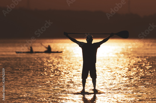 Man practicing stand up paddle at sunset