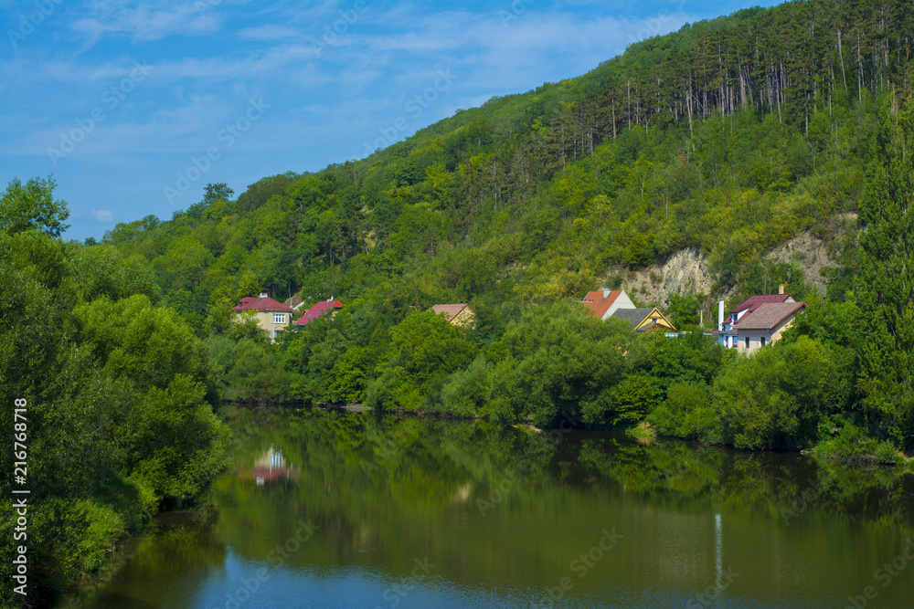 Fototapeta premium The bend of a river with several houses on a hill in Europe