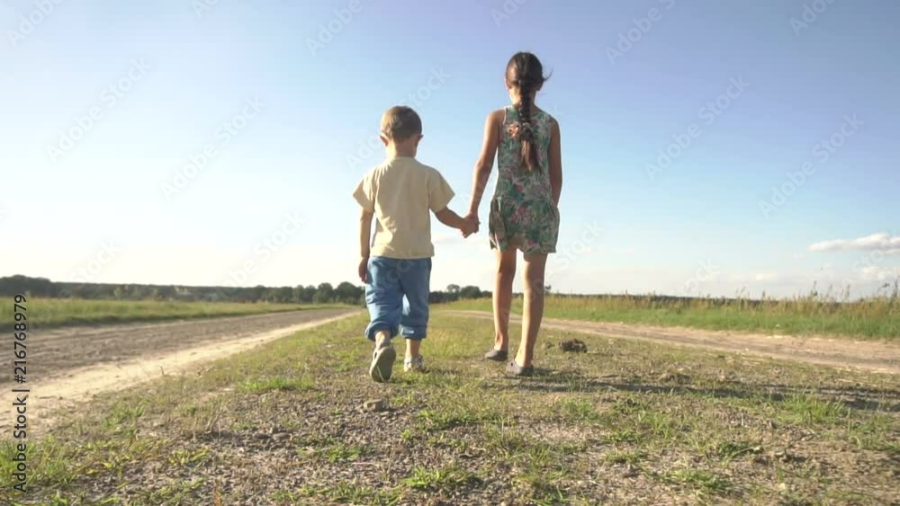 A small boy and girl holding hands are walking along the road A small boy and girl holding hands are walking along the road