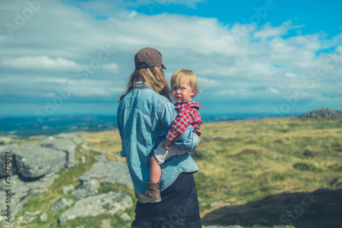 Young mother and toddler admiring view from rock on hill