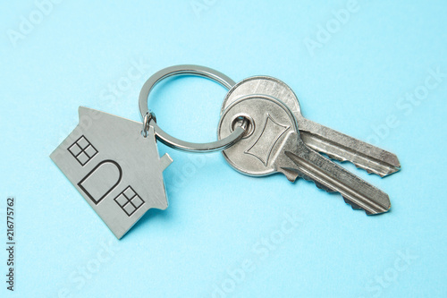 Keys and a keychain house on a blue background. Concept of buying a house, renting © adragan