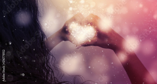 Magic emanating from the hands of a woman  a light effect in the form of hearts in the hands  glare of light  bokeh