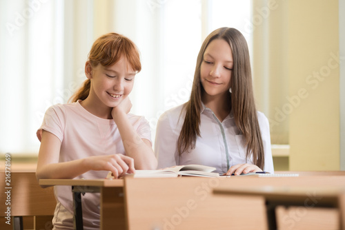 2 student girls are sitting at a Desk