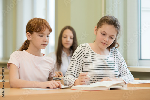 3 student girls are sitting at a Desk