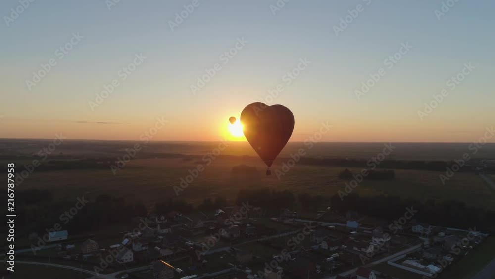 Aerial view Hot air balloon shape heart in sky over field in countryside, beautiful sky and sunset. Aerostat fly over countryside.Aerial footage 4K
