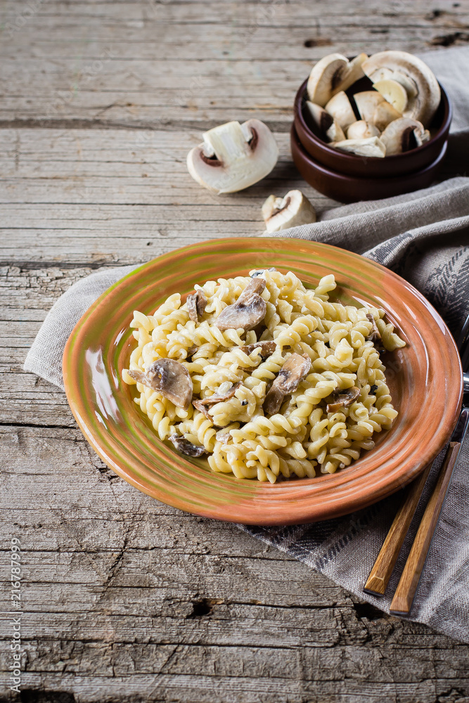 Italian pasta fusili with mushrooms and cream sauce on wooden table, copy space, top view. Autumn Food Concept