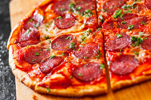 sliced Pepperoni Pizza with Mozzarella cheese, salami, Tomatoes, pepper, Spices and Fresh Basil. Italian pizza