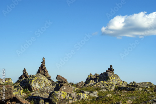 bright landscape of a high-altitude plateau with folded travelers pyramids cairns of stones under a blue sky with clouds photo