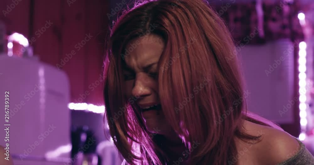 Crying abused woman pleads with someone off screen in her kitchen