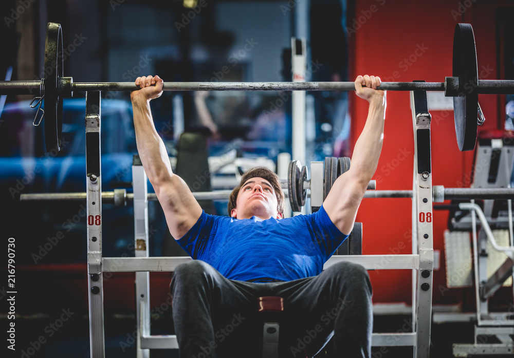 Naklejka premium Man doing bench press in gym