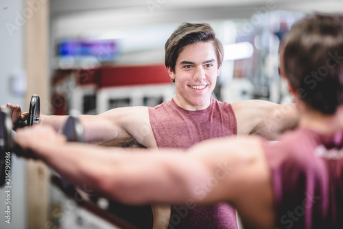 Muscular handsome man with dumbbells in gym