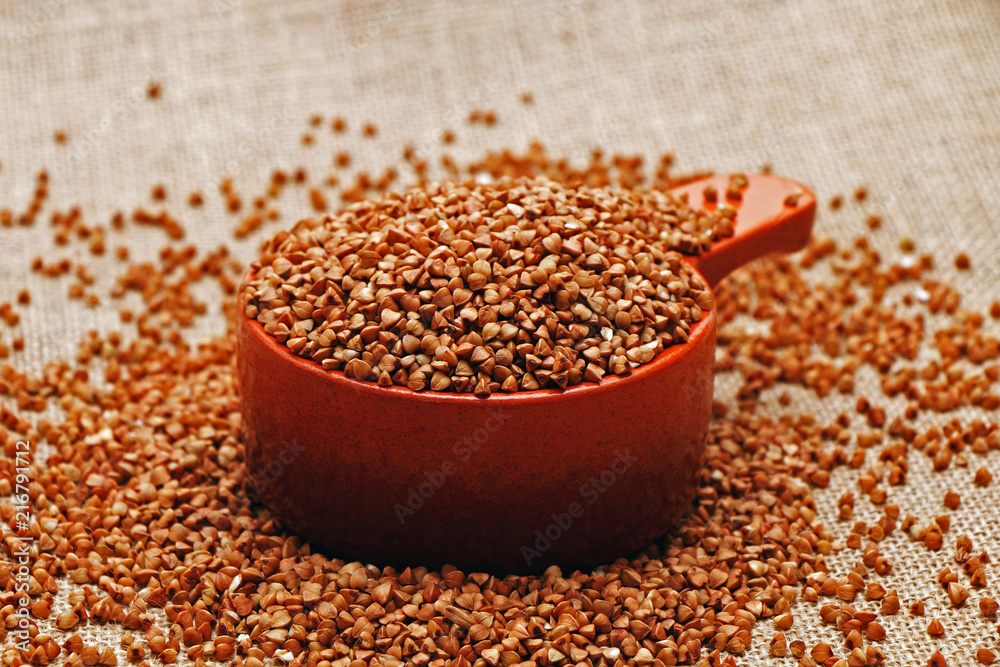 Buckwheat in a clay crock. Against the background of sacking Buckwheat in a clay crock. Against the background of sacking