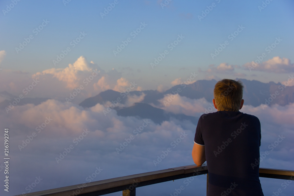 Fototapeta premium A man standing on a wooden platform at sunset high in the mountains of Sochi, Russia, 08/22/2017 