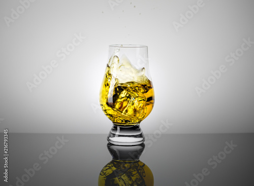 Taster Glass with a Dram of Scotch Whisky and Ice Cube Falling into it.