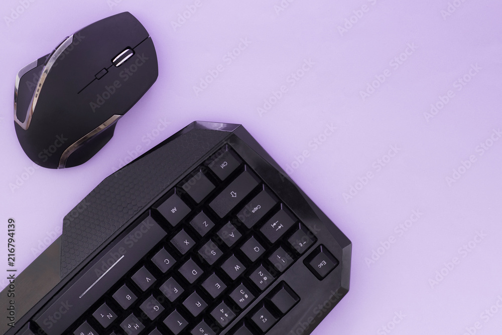 Black mouse and keyboard on a pink background, top view. Workplace, mouse and keyboard flat lay. Computer devices Black mouse and keyboard on a pink background, top view. Workplace, mouse and keyboard flat lay. Computer devices