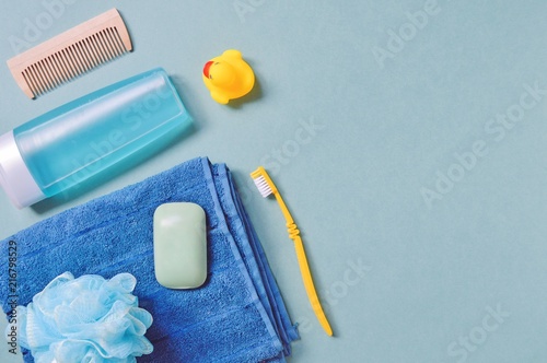 Flat lay photo toiletries set, personal care items/ Wooden hair brush, shower gel or shampoo for men, cotton towel, sponge, soap bar, rubber duck and yellow toothbrush photo