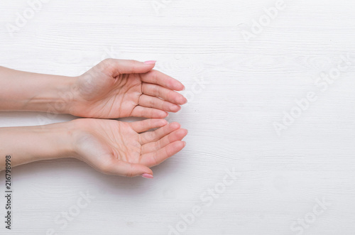 Woman hands ask or give something isolated on white wooden background.