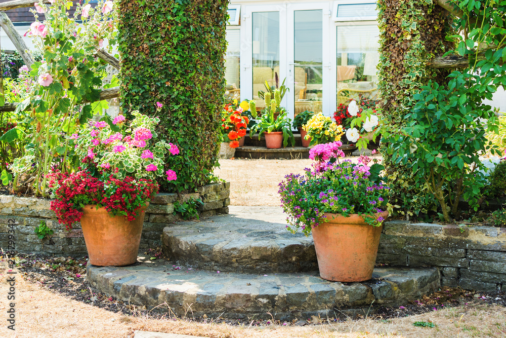 Beautiful backyard garden full of colorful flowers in pots and containers, selective focus