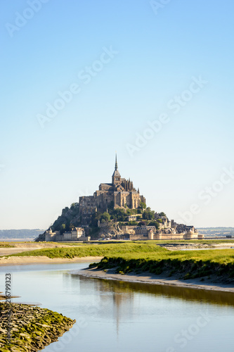 View of the Mont Saint-Michel tidal island, located in France on the limit between Normandy and Brittany, at high tide with the Couesnon river in the foreground.