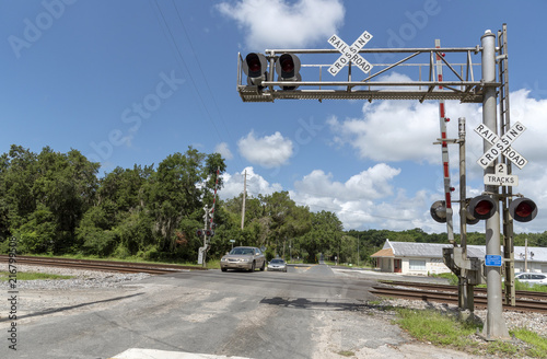 Summerfield, Florida, USA, 2018. Railroad signals and track passing through North Florida countryside. Car crossing the junction.